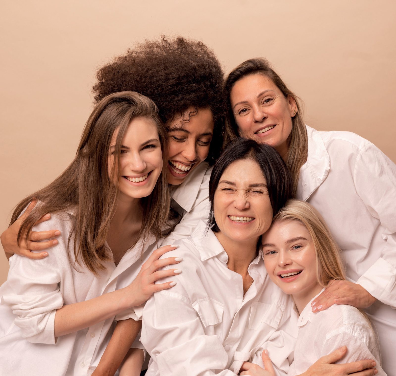 Grupo de mulheres de diferentes idades sorrindo abraçadas