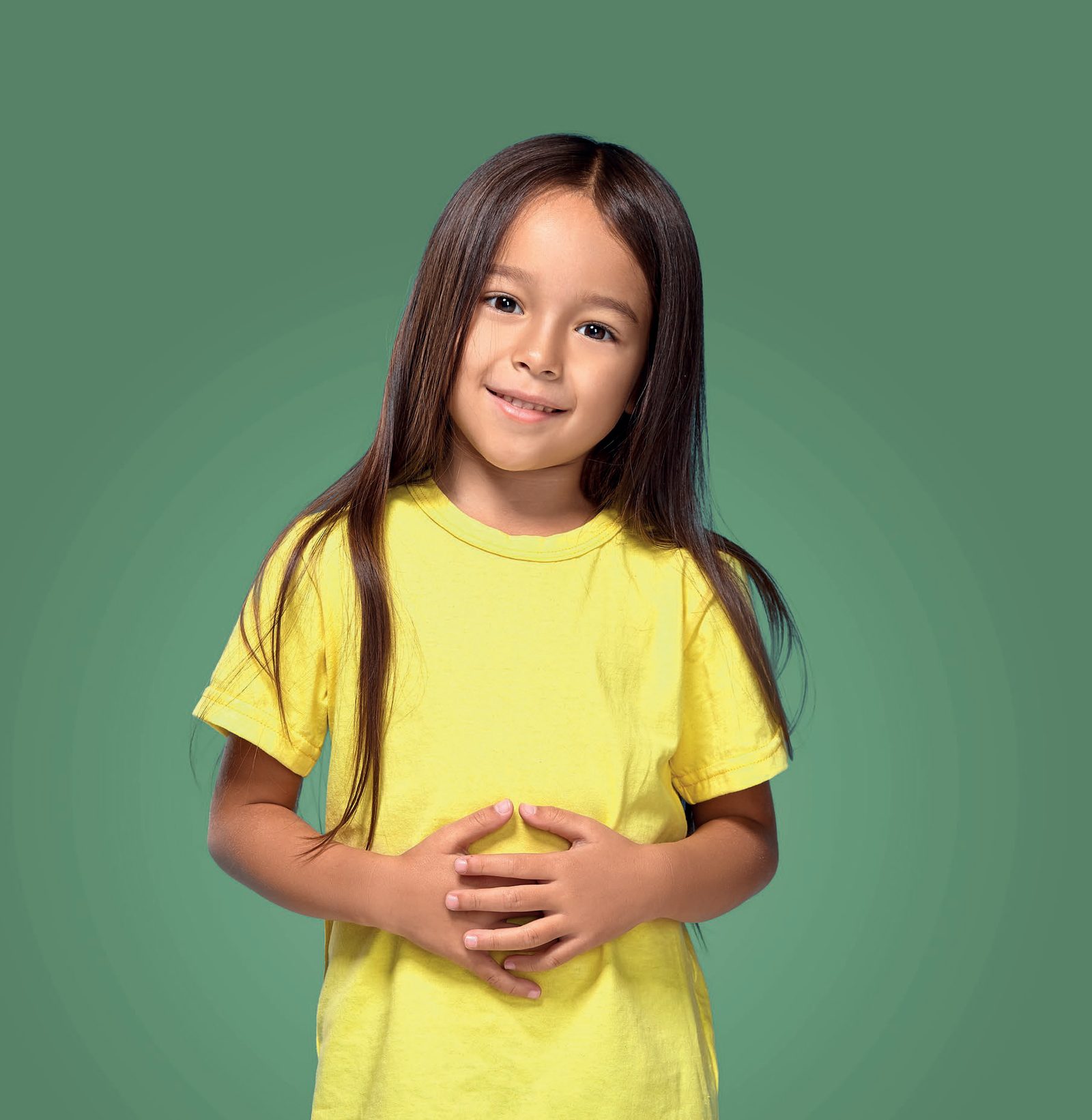 Menina sorridente de camiseta amarela com as mãos sobre a barriga