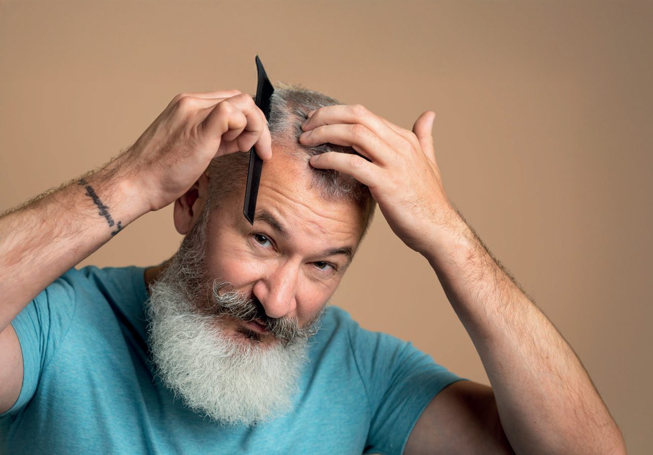 Homem grisalho de barba penteando o cabelo