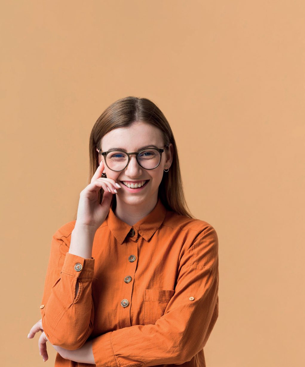 Mulher jovem de óculos sorrindo, com a mão no rosto