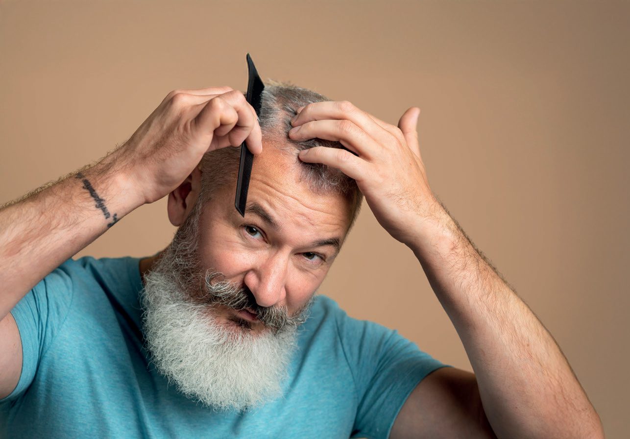 Homem grisalho de barba penteando o cabelo