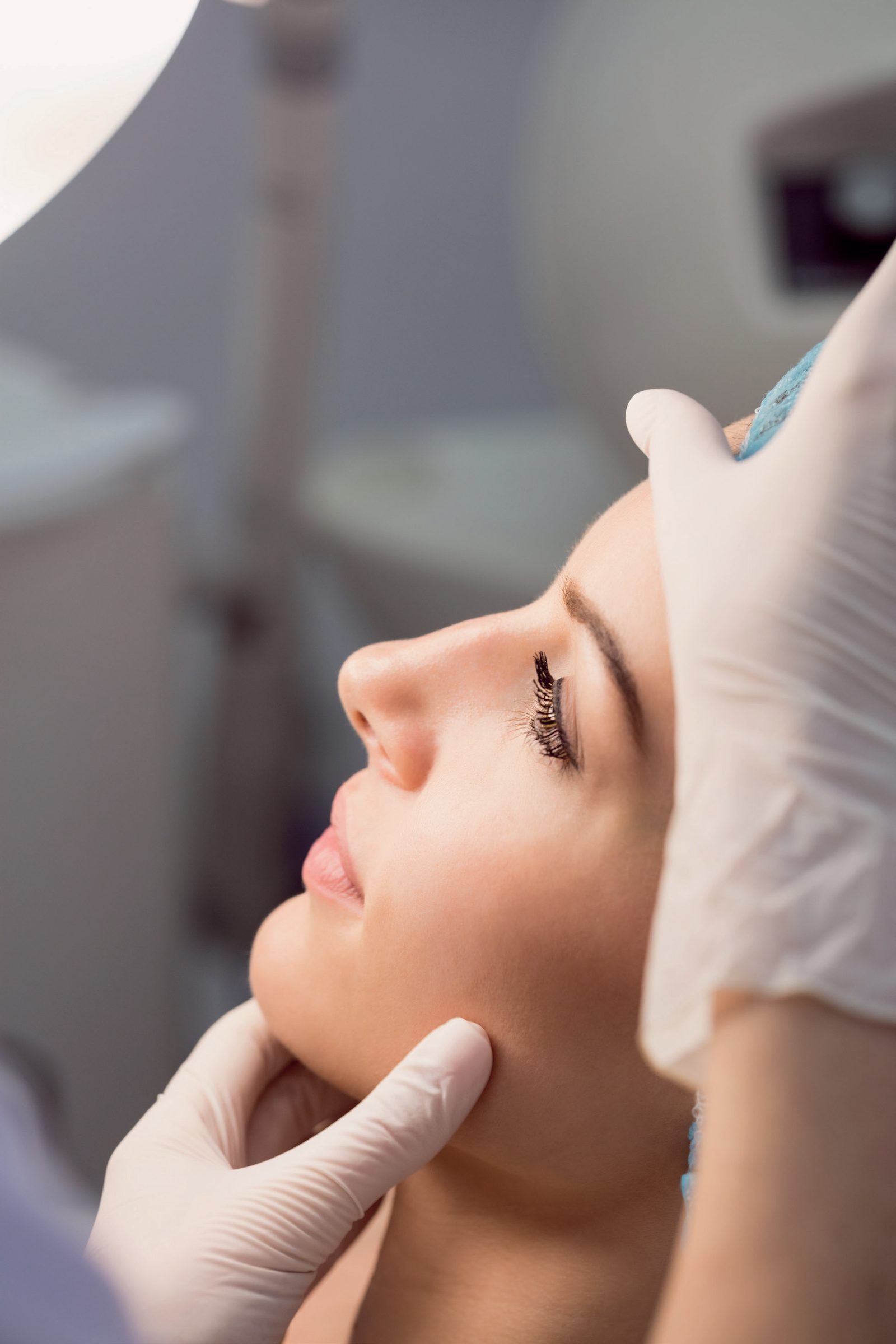 Mulher de perfil recebendo procedimento facial com luvas
